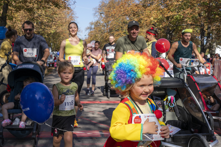 Kinder im Kinderwagen oder laufend und Erwachsene joggen fröhlich beim ROTE NASEN LAUF